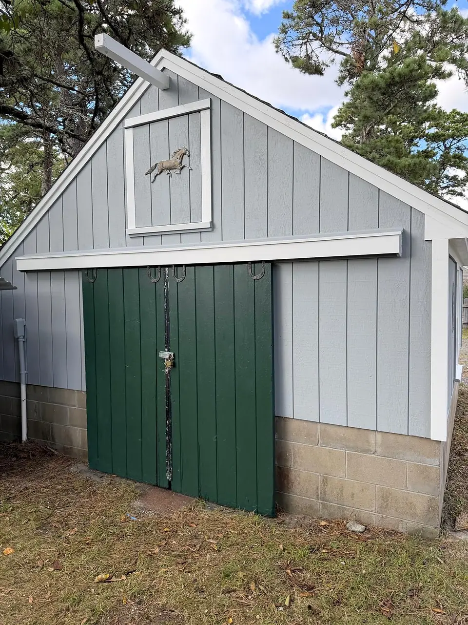 The same barn after repainting: gray siding, white trim and new green doors