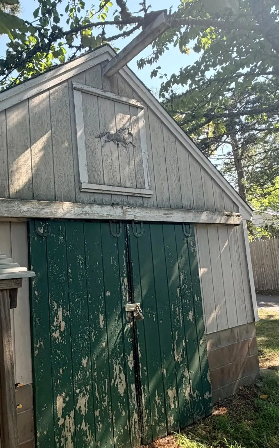 The barn before: paint peeling off the siding and the green doors